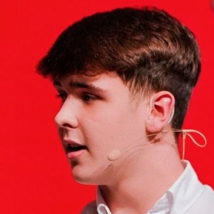 Harrison Nott in close profile, wearing a headset microphone, mid-sentence