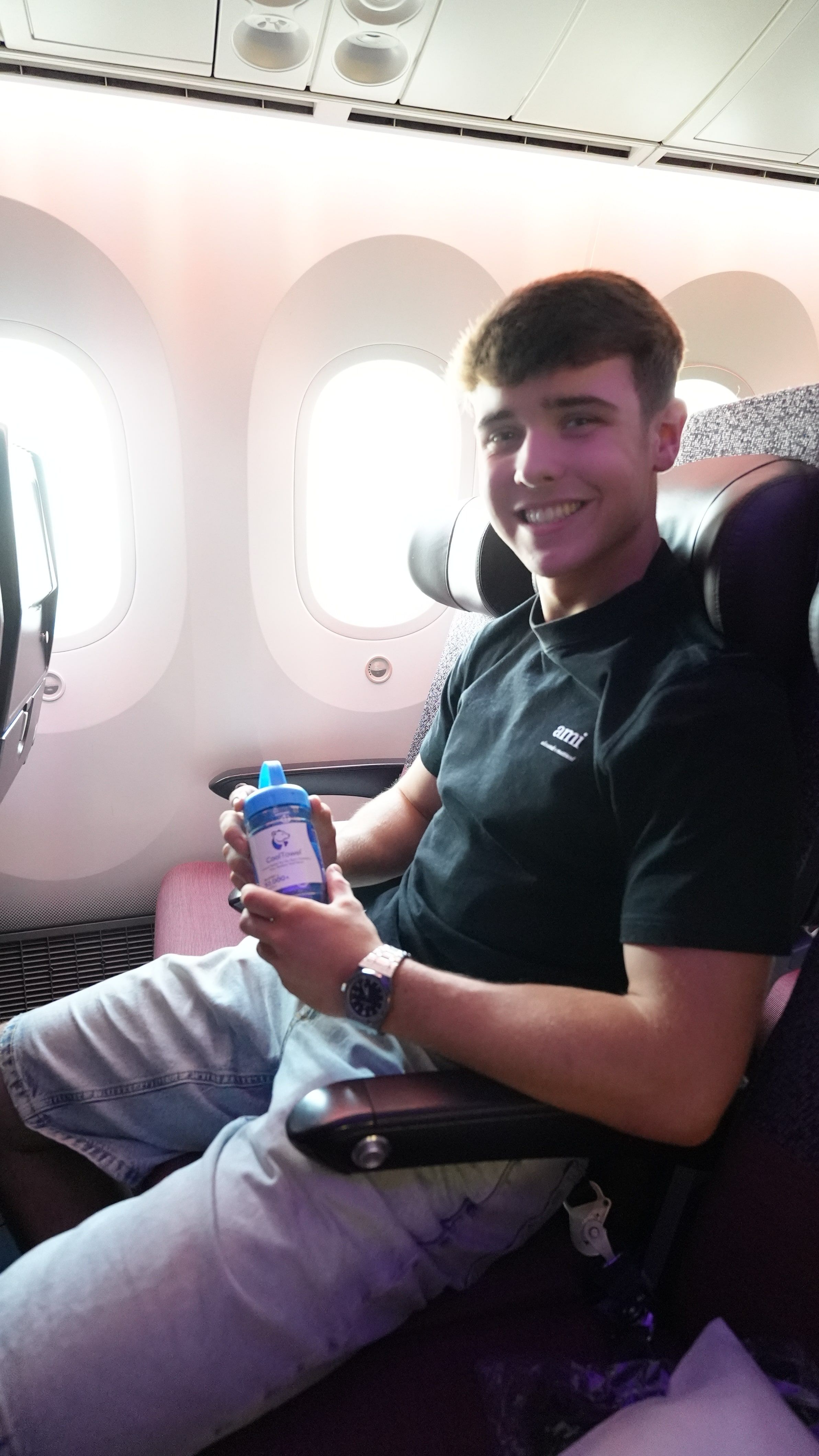 Harrison in a window seat on the flight to Los Angeles, holding a CoolTowel in its tube