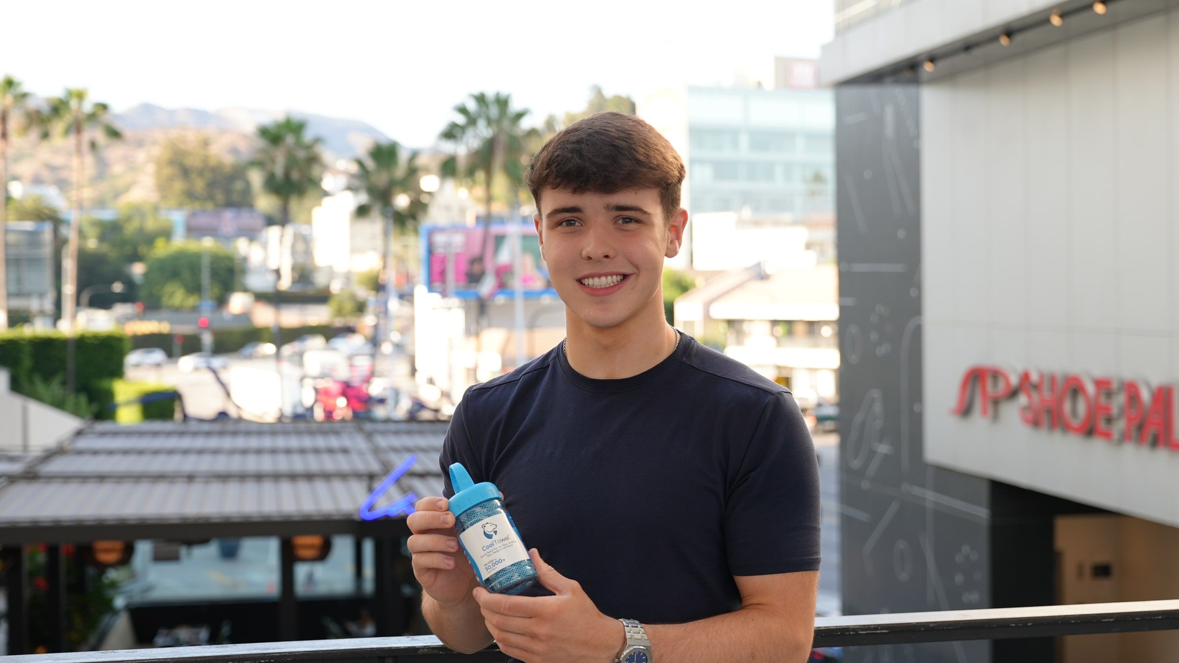 Harrison Nott on a balcony above Sunset Boulevard in Los Angeles, holding a CoolTowel
