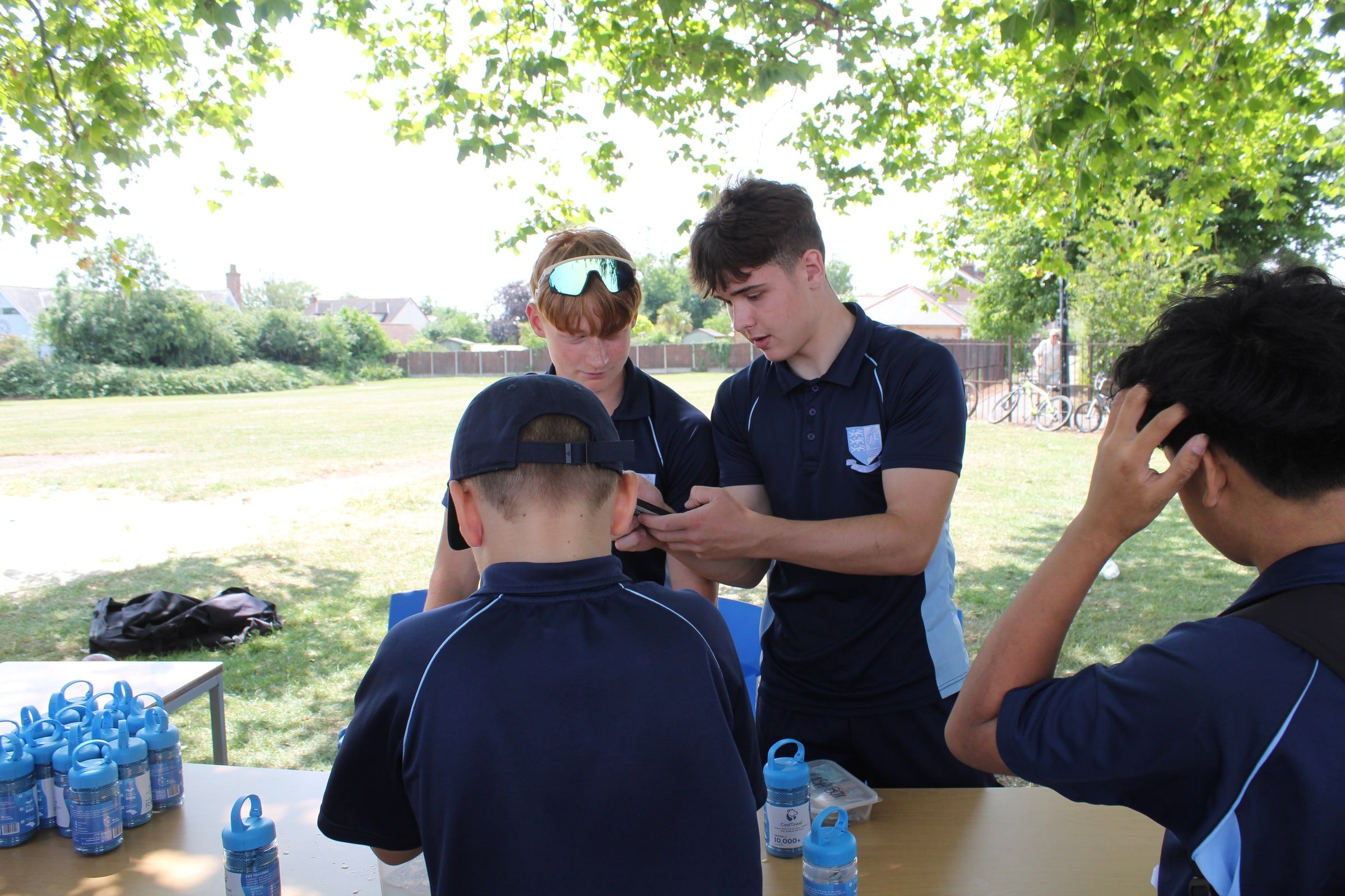 Harrison taking a card payment on his phone at a trestle table of CoolTowel bottles on the school field