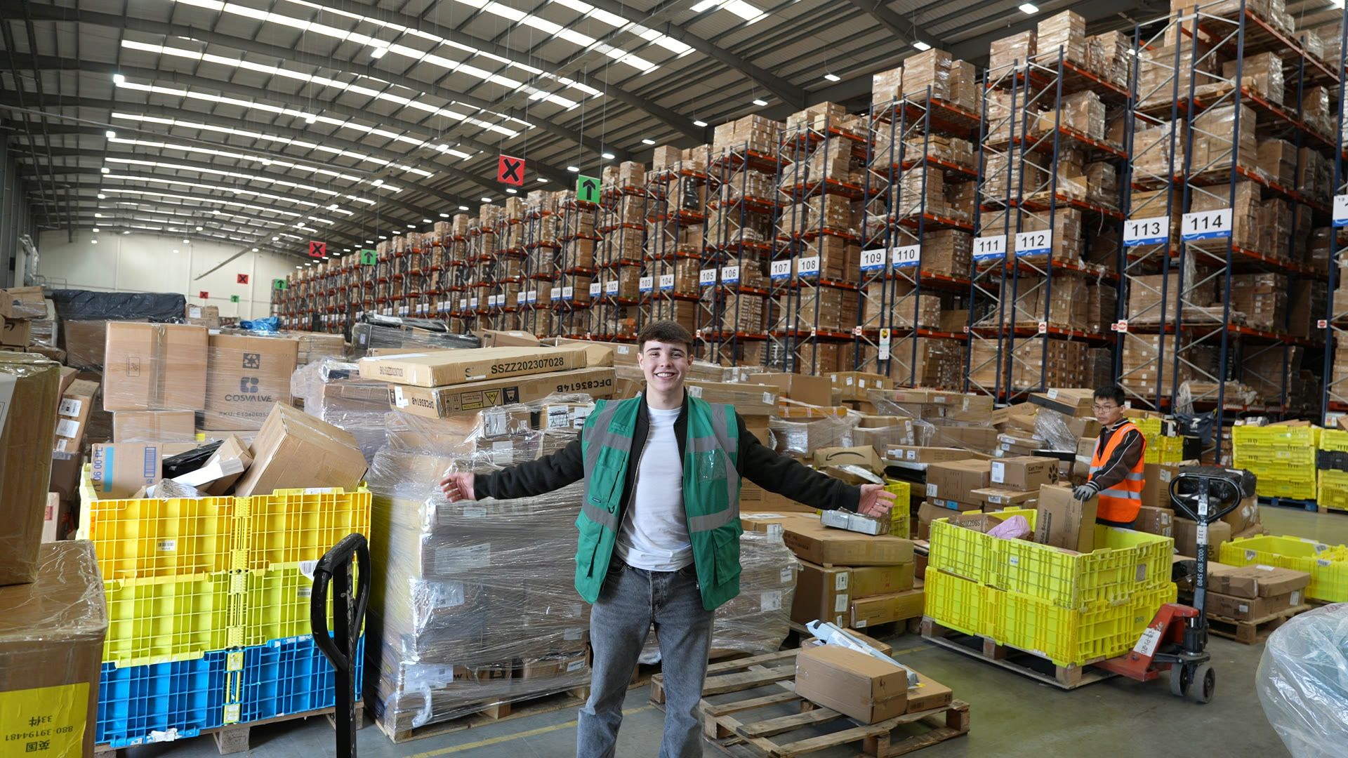 Harrison standing in the warehouse aisle between racking and pallets